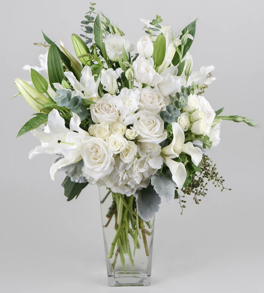 White Roses and accent flowers with lush greenery.